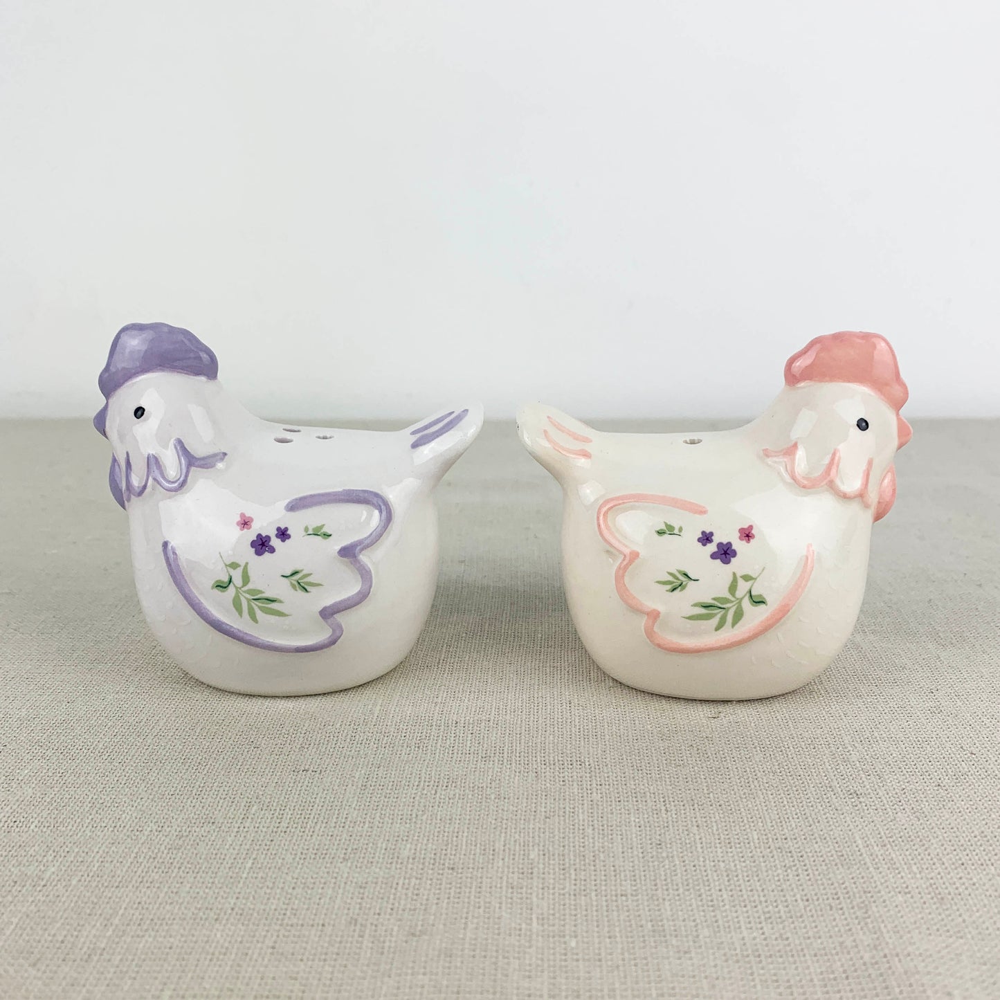 Two ceramic chicken-shaped salt and pepper shakers on a textured surface.