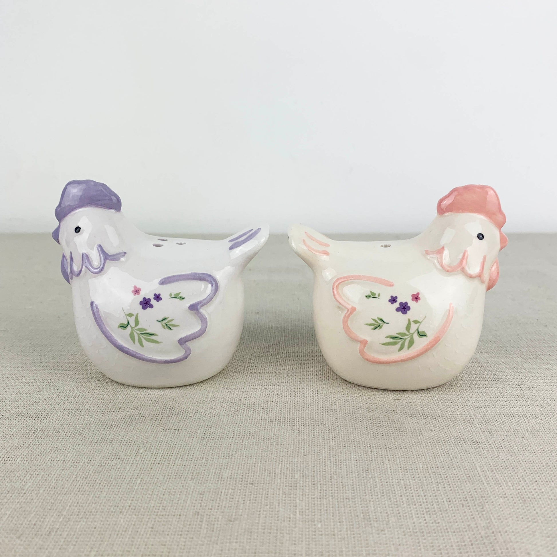 Two ceramic chicken-shaped salt and pepper shakers on a textured surface.