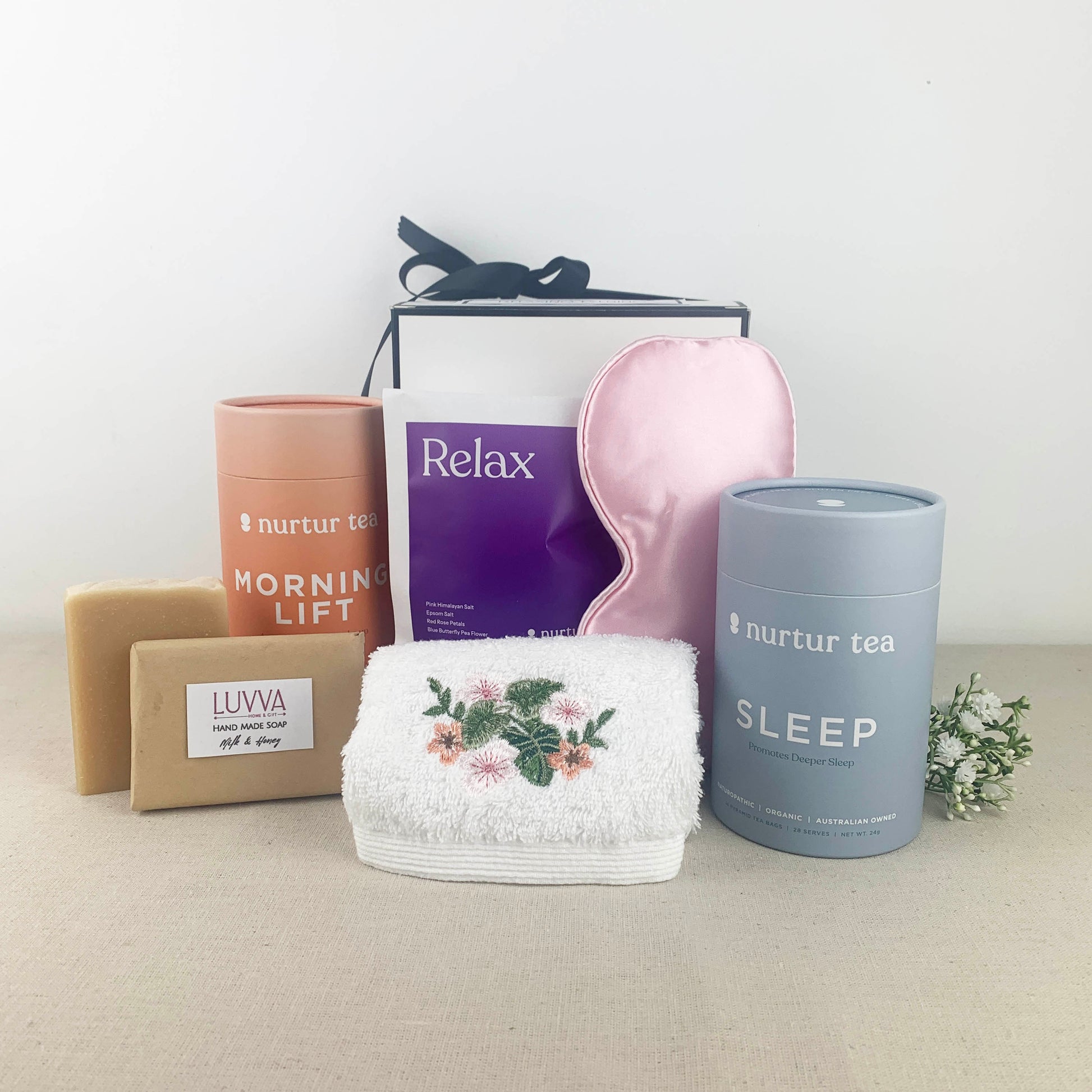 Collection of Luvva self-care items including a sleep mask, towel, and tea