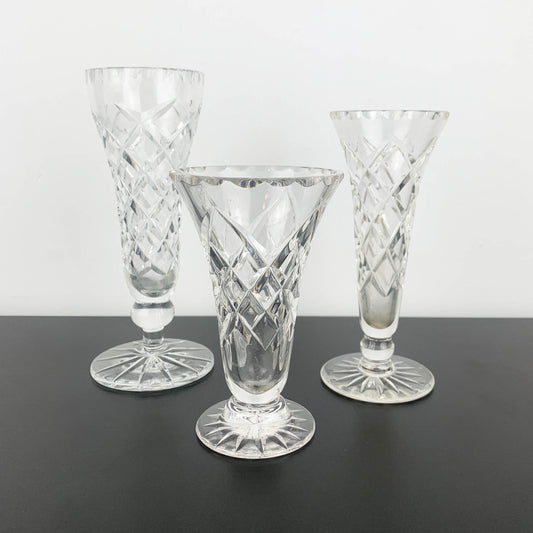 Three crystal glasses with intricate designs on a black surface and white background