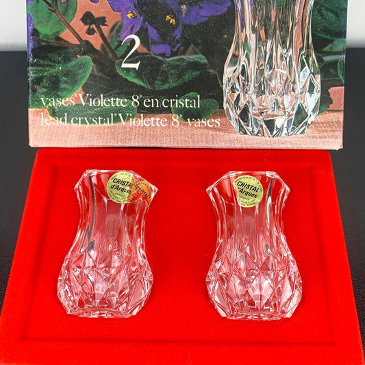 Two crystal vases on a red cushion with packaging in the background