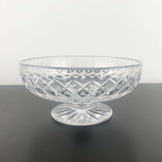 Clear glass bowl with diamond pattern on a dark surface and light gray background