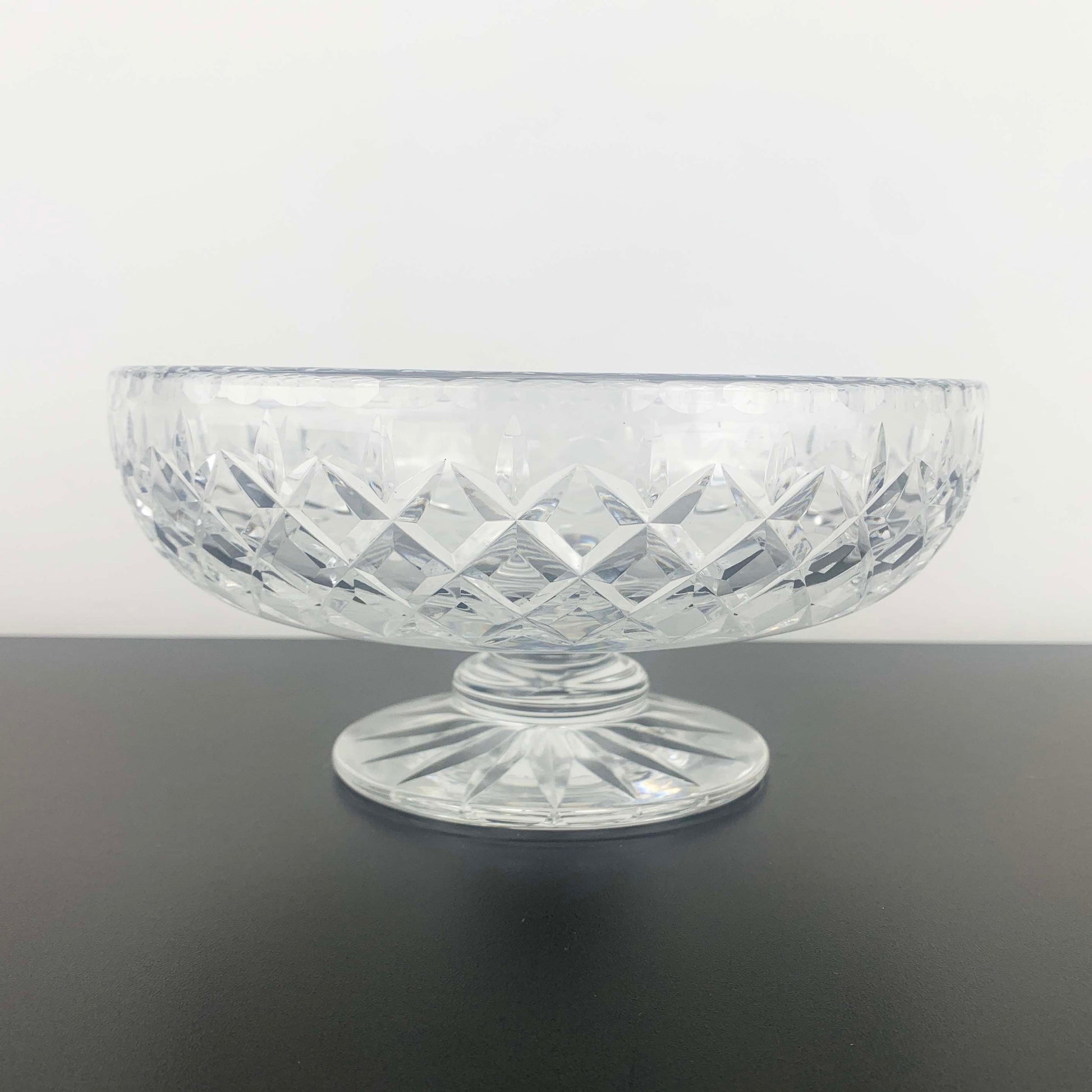 Clear glass bowl with diamond pattern on a dark surface and light gray background