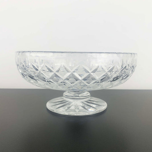 Clear glass bowl with diamond pattern on a dark surface and light gray background